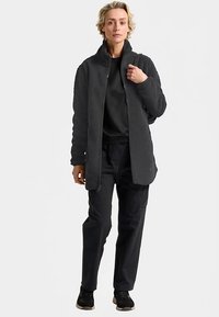 Fleece jacket in gray with a high collar, front zip, and textured fabric. Paired with black pants and shoes, stands against a neutral background.