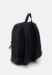 Černý batoh s polstrovanou, texturovanou zadní částí a širšími popruhy. Disponuje hladkým materiálem a boční kapsou na zip. Jednoduchý a funkční design.