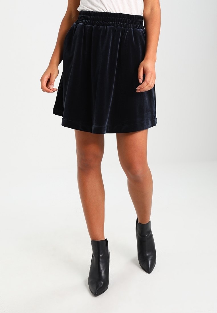 Marinblå sammetkjol med elastisk midja, utsvängd design och mjuk textur, kombinerad med svarta ankelskinnstövlar.