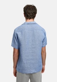 Kortermet skjorte med krage i lys blå, laget av strukturert stoff. Har en rett kutt, subtil søm og ingen synlige mønstre.