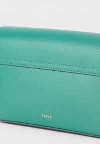 Turquoise leather wallet with a textured surface, featuring a gold "Furla" logo and clean, minimalistic design with precise stitching.
