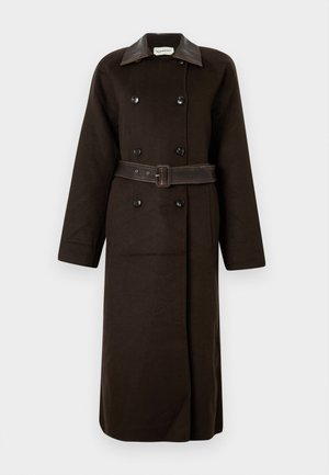 Ilgas tamsiai rudas dvigubo užsegimo paltas su juodais mygtukais, platus odinis apykaklė ir atitinkamas diržas, susagstytas ties liemeniu.