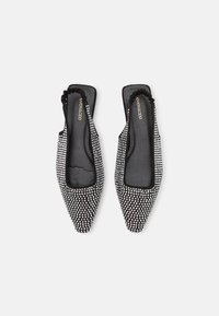 Bailarinas de fondo negro y blanco con un tejido texturizado y pequeños patrones cuadrados, diseño de punta afilada y parte trasera suave con volantes.
