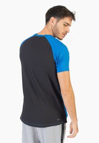 Camiseta atlética de manga corta que presenta una parte superior azul y una sección inferior negra con un patrón texturizado, confeccionada en una tela ligera.