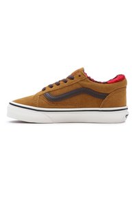 Zapatilla baja de ante marrón con acentos marrones oscuros, que presenta un forro rojo de felpa, cordones negros y una suela blanca con una franja negra.