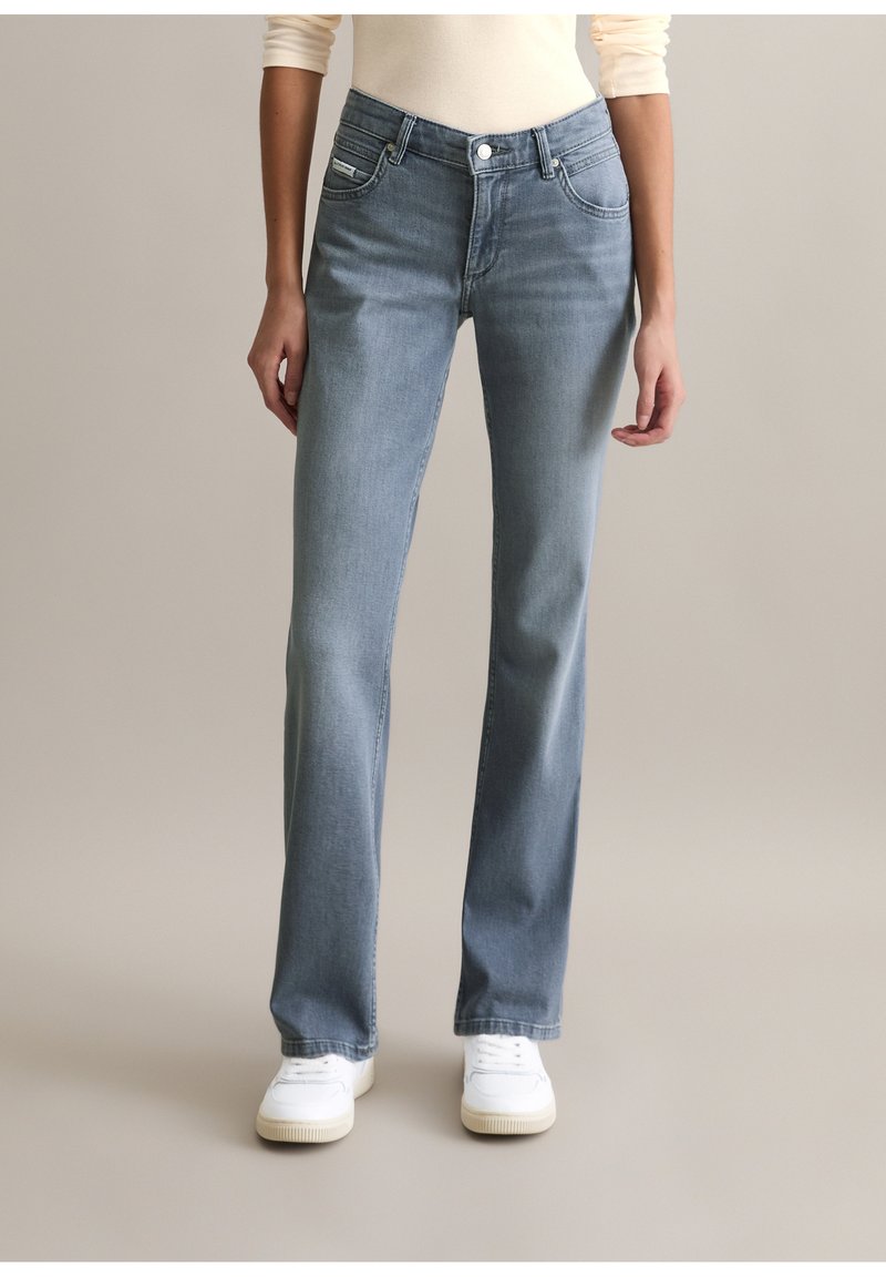 Lichtblauwe spijkerbroek met een rechte pijp, voorzien van voorzakken, een knoopsluiting en subtiele verweerde details. Gecombineerd met witte sneakers.