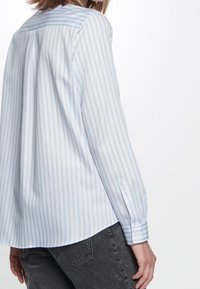 Ljusblå och vit randig blus i mjukt tyg, med krage, långa ärmar och knappade manschetter, med en avslappnad passform.
