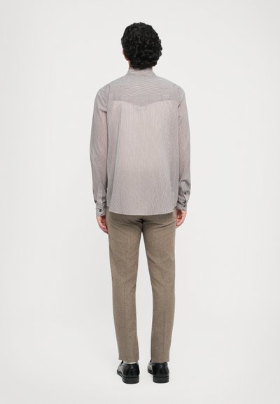 Heledatud hall pitsiga triibulisest nupuga särk, mis on kombineeritud pruunide tekstuuriga pükstega. Kujunduses on tagumine otse ja varrukate äärised.