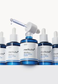 Trzy niebieskie szklane butelki serum Medicube Zero Pore One Day, każda z białym zakraplaczem i białymi etykietami zawierającymi informacje o produkcie.