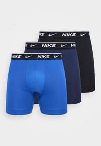 Τρία ζευγάρια μπόξερ Nike σε μπλε, ναυτικό και μαύρο, με μαύρες ελαστικές μέσες που φέρουν λευκά λογότυπα Nike και swoosh.