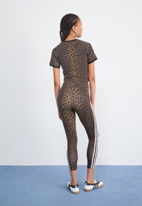 Set di abbigliamento attivo con stampa leopardata composto da una maglietta a maniche corte e leggings abbinati con strisce laterali bianche. Tessuto morbido e elastico, design aderente.