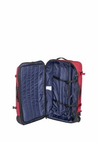 Valise à roulettes rouge avec un extérieur en tissu, dotée d'une doublure intérieure bleue, de plusieurs sangles et d'une poche zippée sur un côté.