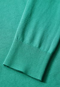 Türkis gestrickter Pullover mit Rippbündchen und strukturiertem Stoff. Weiches, dehnbares Material mit glatter Oberfläche und gleichmäßiger Farbe.