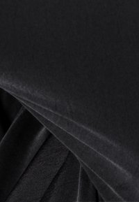 Svart tyg med en slät yta, med veck för extra dimension och en subtil lyster. Materialet verkar mjukt och mångsidigt.
