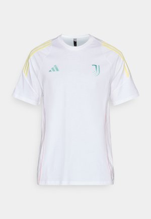 Hvit kortermet skjorte med kontrasterende gule akcentstriper på skuldrene. Har brodert grønn logo på brystet og rosa side-søm.