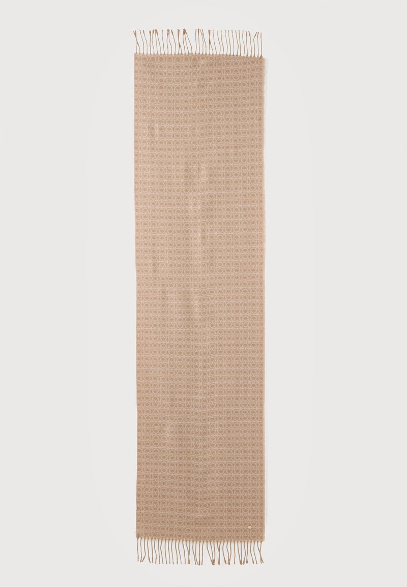 Longue écharpe beige avec une texture à motifs subtils et des franges aux deux extrémités sur un fond uni.