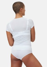 White moisture-wicking athletic shirt with short sleeves, featuring a textured back and a fitted design, paired with matching white bottoms.