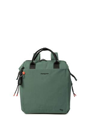 Sac à dos vert en forme carrée avec des poignées noires, des tirettes de fermeture éclair noires avec des bouts rouges, et le nom de la marque Hedgren au centre avant.