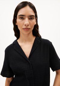 Zwarte short-sleeve-shirt met een gestructureerde stof, kraaghals en knoopsluiting. Eenvoudig ontwerp met een relaxed fit.