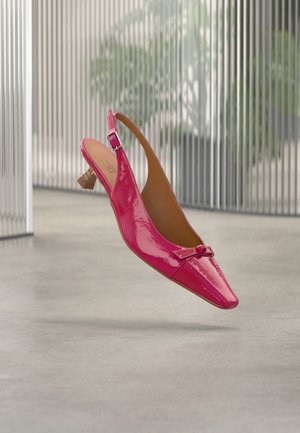 Sjöajnasti ružičasti slingback s niskom drvenom petom i malom ukrasnom mašnom na špicastom prstu, postavljen na zamagljenoj unutarnjoj pozadini.