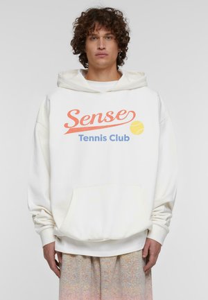Fehér kapucnis pulóver elülső zsebbel, narancssárga és kék "Sense Tennis Club" felirattal, teniszlabda grafikával, puha anyagból készült.