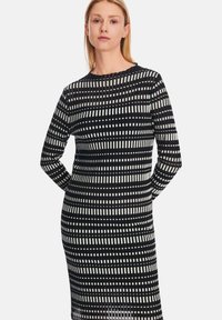 Langärmliges Kleid mit einem schwarz-weißen Streifenmuster in unterschiedlichen Breiten. Hergestellt aus einem glatten Stoff, mit einem Rundhalsausschnitt.