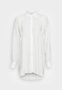 Camicia bianca a maniche lunghe con chiusura a bottoni, colletto classico e dettagli sulle spalle a palloncino. Tessuto leggero e vestibilità rilassata.