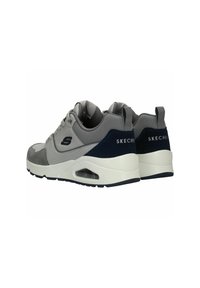 Scarpe sportive grigie realizzate in materiali in rete e suede, con un intersuola bianca e accenti blu navy. Presentano dettagli del logo e ammortizzazione ad aria.