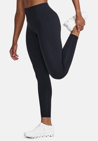 Schwarze hochgeschnittene Leggings mit nahtlosem Design und Flachnähte, kombiniert mit weißen Sportschuhen. Glatter, dehnbarer Stoff.