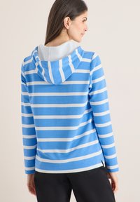 Hoodie rayé bleu et blanc avec cordon de serrage, manches longues, et texture de tissu doux, avec une couleur intérieure contrastante.