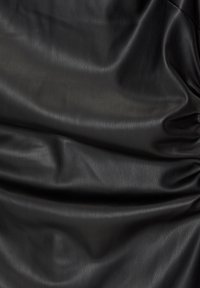 Tissu en cuir lisse noir avec des plis naturels et une texture subtile, mettant en valeur ses propriétés matérialles douces et flexibles.