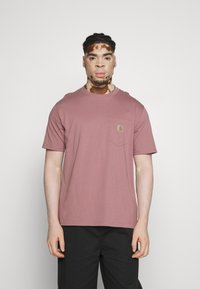 T-shirt à manches courtes, col rond en rose poussiéreux, avec une poche sur la poitrine gauche et un patch logo. Tissu en coton lisse avec une coupe décontractée.