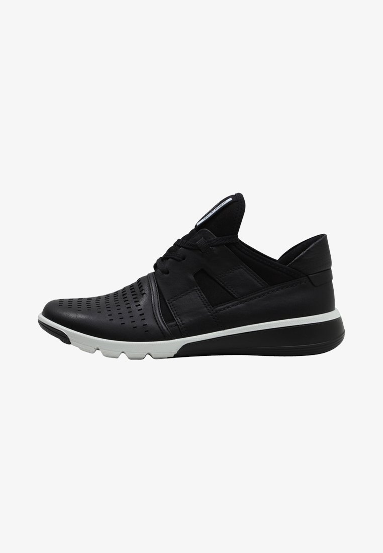 Chaussure de sport noire avec embout perforé, design à lacets, semelle blanche et noire, et col rembourré, vue de côté.
