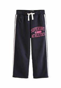 Pantaloni della tuta blu navy con strisce laterali bianche e logo rosa "SUPERDRY ATHLETICS". Tessuto morbido con vita elastica e coulisse regolabile.