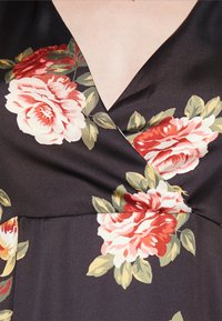 Vestido de cetim preto com decote em V, padrão floral com rosas vermelhas e brancas e folhas verdes; textura suave e caimento macio.