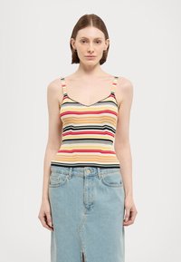 Gestreiftes Tanktop mit V-Ausschnitt, das horizontale Streifen in Rot, Gelb, Schwarz und Weiß zeigt. Kombiniert mit einem hellblauen Jeansrock.