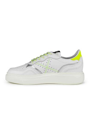 Witte leren sneaker met grijze accenten, geperforeerde details en felgroene veters. Heeft een dikke witte zool en een contrasterende hakkap.