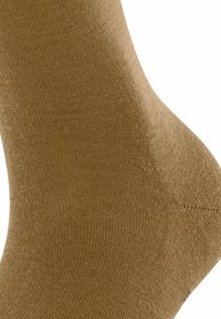 Nahaufnahme eines braunen, gerippten Strumpfes, der einen Fuß und Knöchel bedeckt, mit sichtbarer Textur und Stoffdetails.