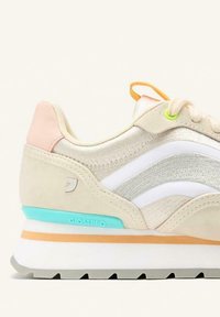 Scarpa da corsa beige con tomaia in suede e tessuto, dettagli bianchi e argento, dettaglio blu chiaro nel tallone, retro rosa e anello arancione.