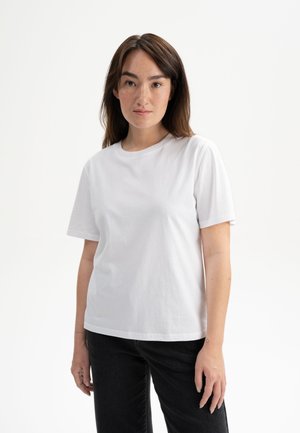 White cotton t-shirt with short sleeves, round neckline, and a relaxed fit, worn with dark jeans, featuring smooth texture and no visible patterns.