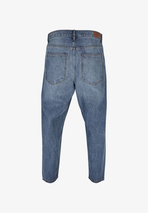 Sinine teksapükste tagantvaade, millel on kaks tagataskut ja pruun nahkstuppert vöörihma peal, kitseneva säärekujundusega.