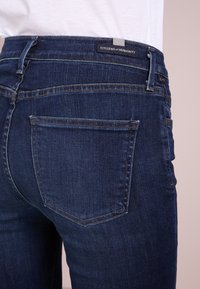 Tmavě modré džíny slim fit s klasickým pětikapsovým designem a štítkem s nápisem "Citizens of Humanity" na pasu.