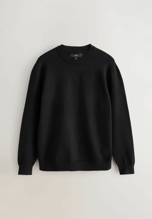 Juodas megztas džemperis su apvaliu kaklu, ilgomis rankovėmis, susiraukšlėtimi ant rankovių ir apvadų. Lygus paviršius be matomų raštų ar akcentų.