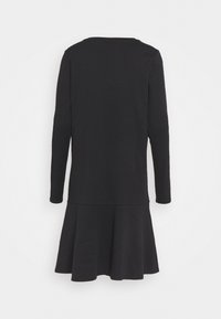 Robe noire à manches longues avec taille basse et jupe évasée, vue de dos sur un fond blanc uni.