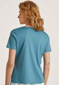 Teal katoenen T-shirt met korte mouwen en een ronde halslijn, met een gladde textuur en een casual pasvorm, gecombineerd met een patroonrok of broek.