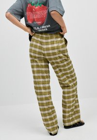 Gröna rutiga byxor med en lös passform, som har ett rutig mönster i ljusa och mörka nyanser, matchade med en grafisk oversized t-shirt.