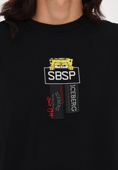 Sort bomulds t-shirt med en broderet SpongeBob design, der holder et skilt med "SBSP," sammen med teksturerede Iceberg mærkepatches.