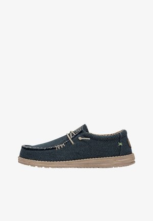 Scarpe slip-on in tela blu texturizzata con suola in gomma beige, cuciture a contrasto e un piccolo logo verde sul lato.