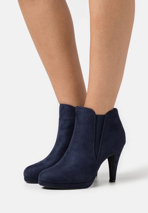 Navy blue suede ankle boots with a pointed toe, slim high heels, and elastic side panels for easy wear. Smooth texture, minimal detailing.