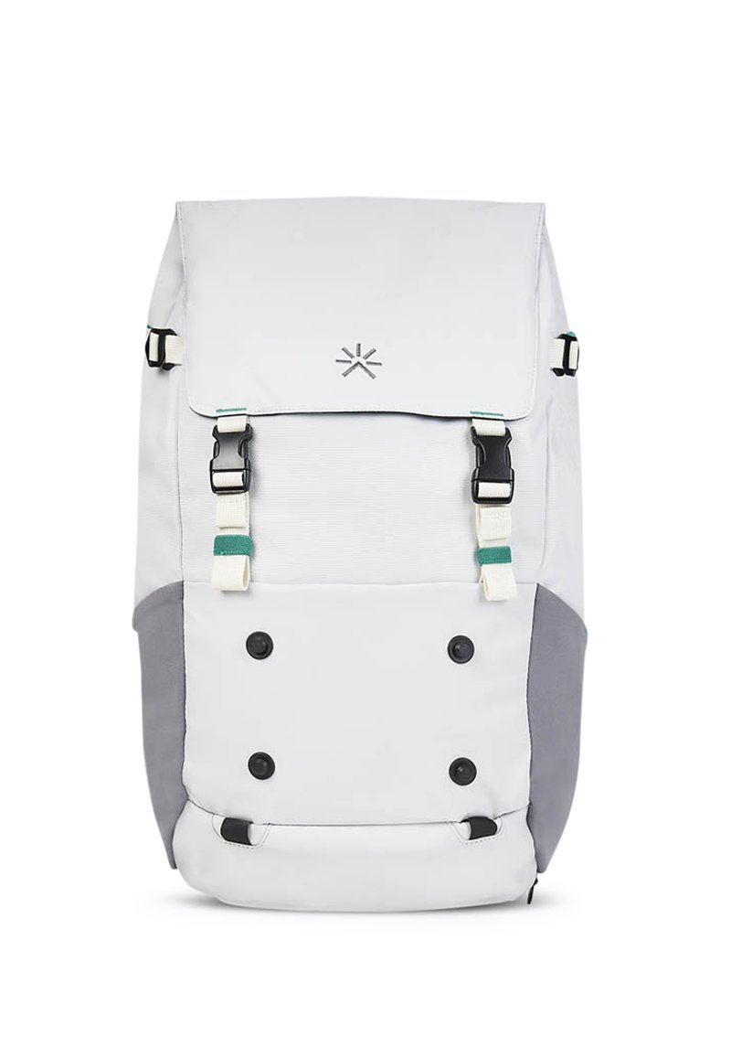 Mochila de tela blanca con acentos grises, cierre tipo cincha y dos correas frontales. Presenta un logo y seis detalles de botones negros.